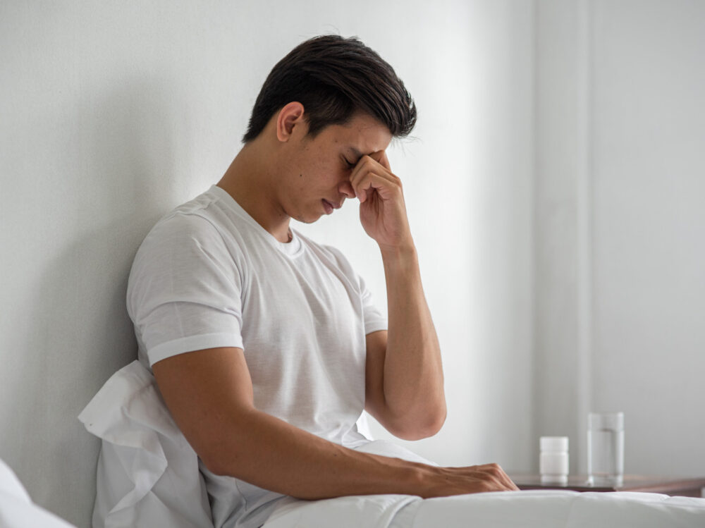 A man with migraines holds her hand by his nose in the bed. A man with migraines holds her hand by his nose in the bed.