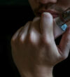 Man with concealed identity smoking a controversial vaping an electronic cigarette. Vaping is debatable in the health community if it is safe or a health risk