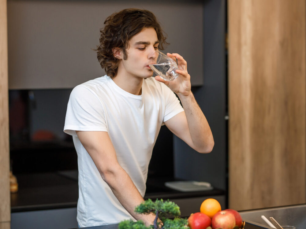 Handsome guy stay on modern kitchen, drinking glass of water in Handsome guy stay on modern kitchen, drinking glass of water in the morning time.